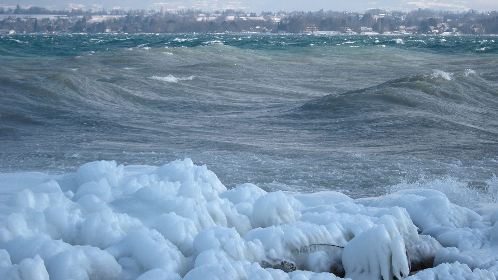 The ice-covered shore of Lake Geneva in winter, with waves whipped up by the bise