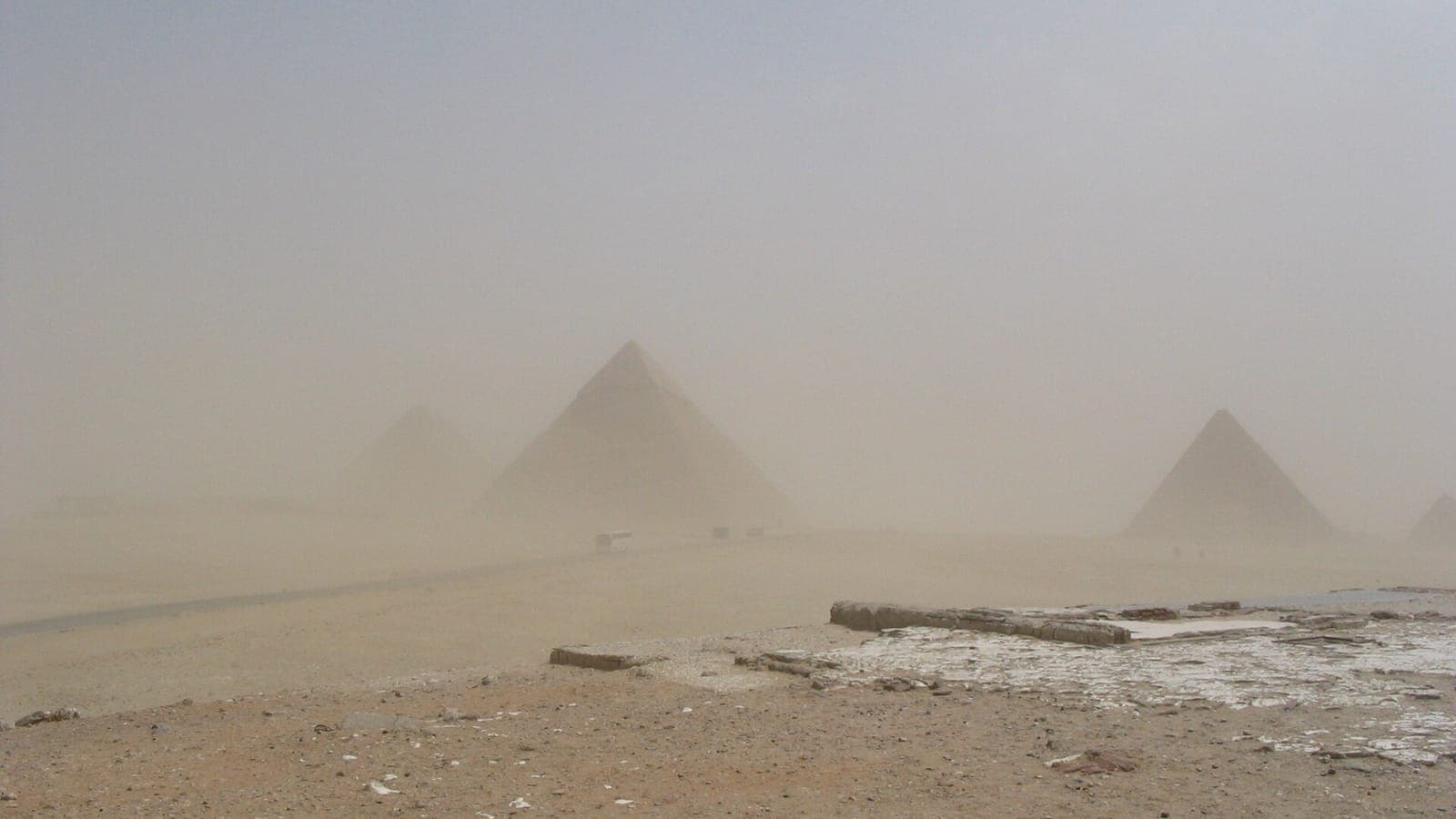 The Giza pyramids fading behind a sandstorm